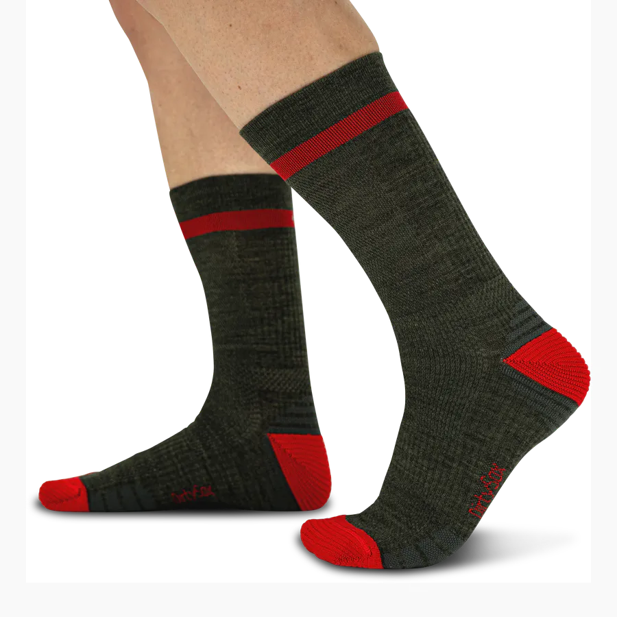 Dunkle, graphitfarbene Socken mit roten Akzenten, an den Unterschenkeln getragen. Wadenhoch mit rotem Querstreifen am Bündchen sowie leuchtend roten Verstärkungen an Zehen und Fersen. Grob gestrickte, robuste Textur.