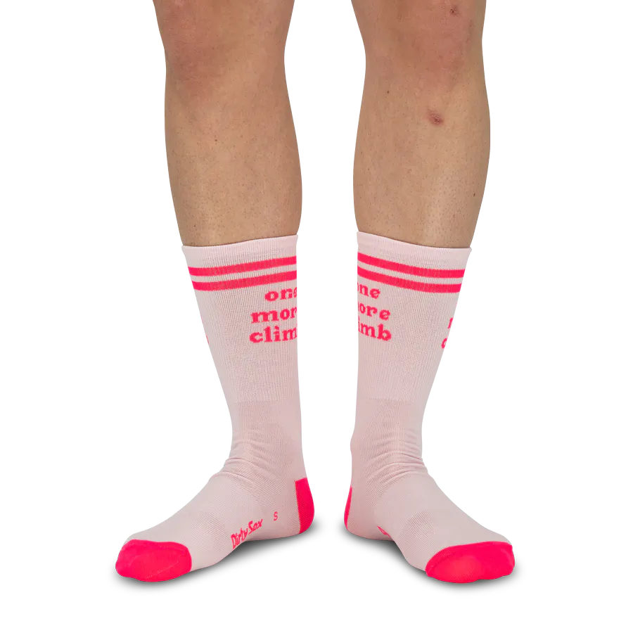 Zwei Beine von Knie bis Fuß, die knielange, hellrosa Socken tragen. Die Socken haben oben zwei leuchtend pinke Streifen und den Text 'one more climb' in ebenfalls leuchtendem Pink. Zehen und Fersen der Socken sind leuchtend pink.