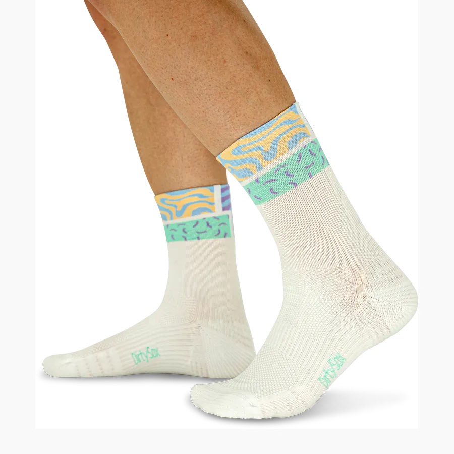 Cream-coloured socks with a vibrant ‘Color Pop’ design at the ankles, featuring a ‘Pastel Flow’ pattern in yellow, light blue and mint green. Fine texture, shown on a person’s feet; the ‘DirtySox ’ logo is visible on the soles.
