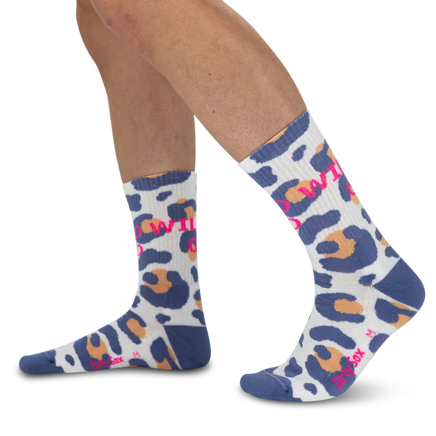 White socks with a leopard print in blue and light orange, shown on standing legs. ‘GO WILD’ is printed vertically in bright pink on both socks. The heels and toes are trimmed in dark blue.